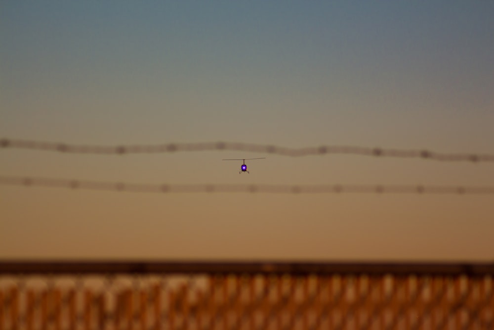 a small airplane flying over a wooden fence