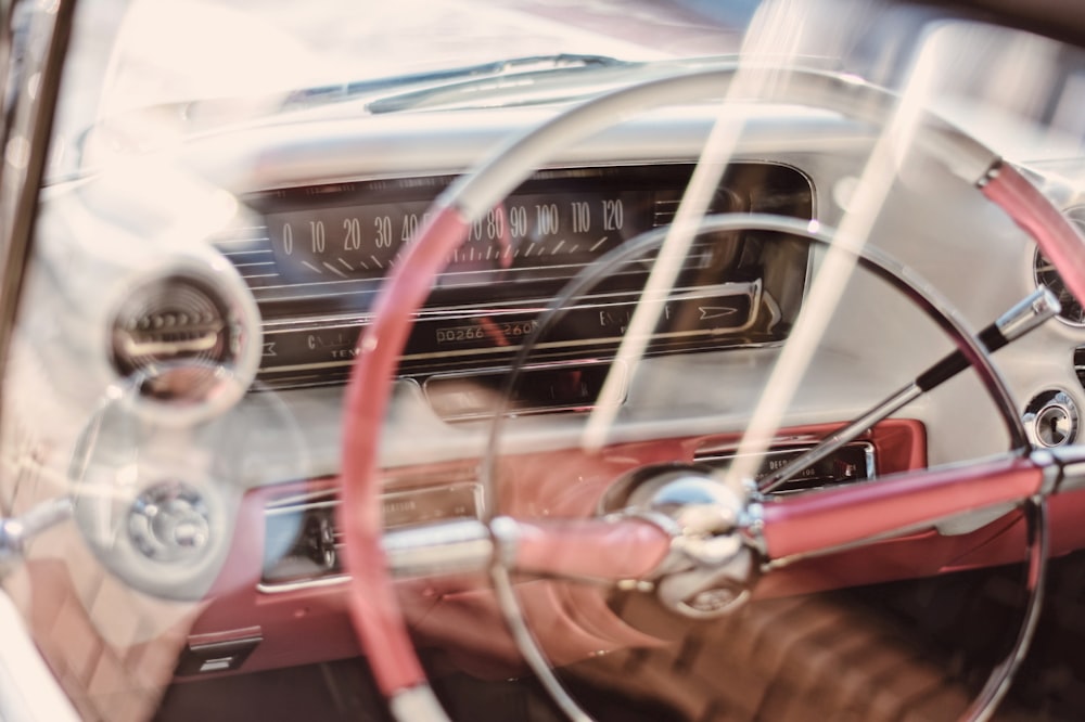 The steering wheel and dashboard inside an older car.