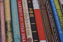 A collection of classic books with various titles lined up vertically, showcasing their colorful and patterned spines. Each spine features unique typography and designs, indicating a mix of genres and authors.