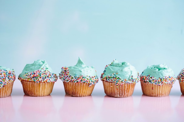 six teal icing cupcakes with sprinkles