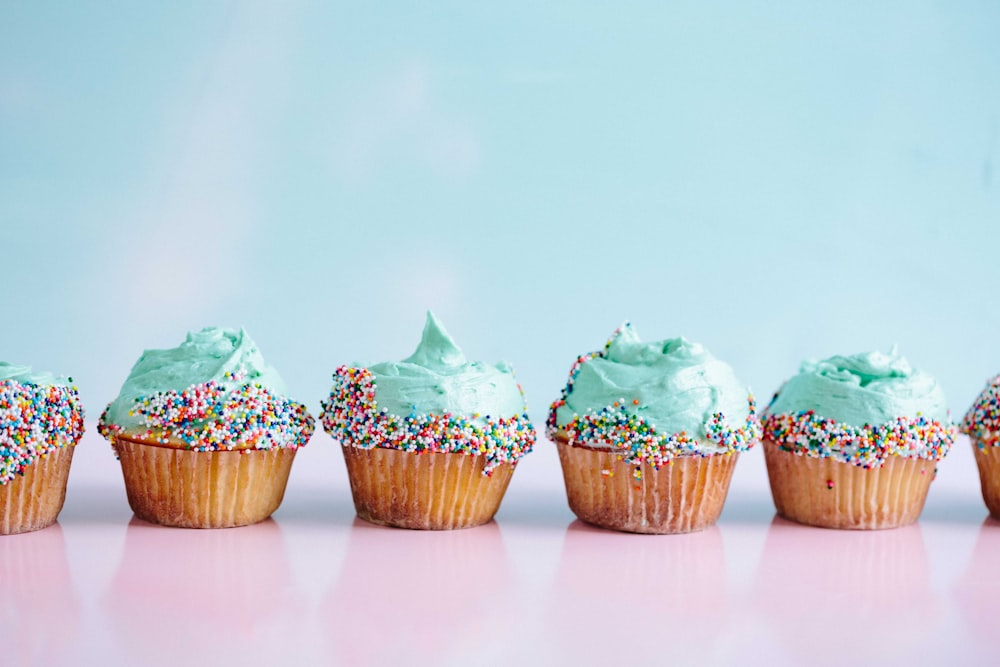 Seis cupcakes de glaseado verde azulado con chispas