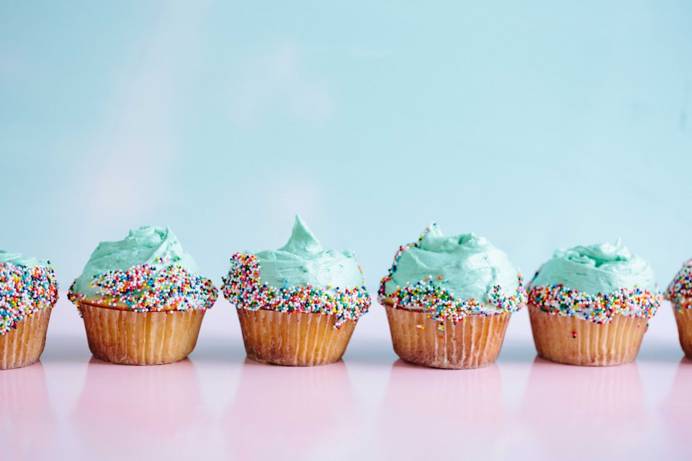 six teal icing cupcakes with sprinkles