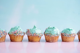 six teal icing cupcakes with sprinkles