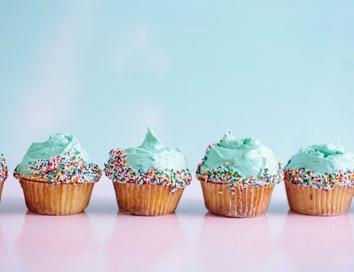 six teal icing cupcakes with sprinkles