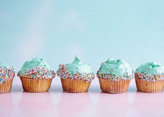 six teal icing cupcakes with sprinkles