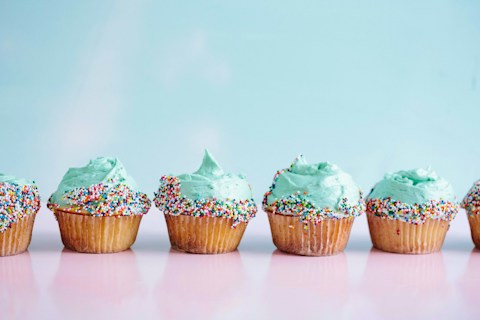 A row of cupcakes with mint frosting and sprinkles