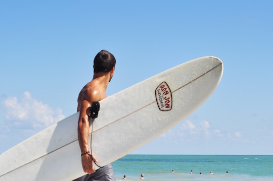 topless man carrying white surfboard in beach during daytime in Florida United States