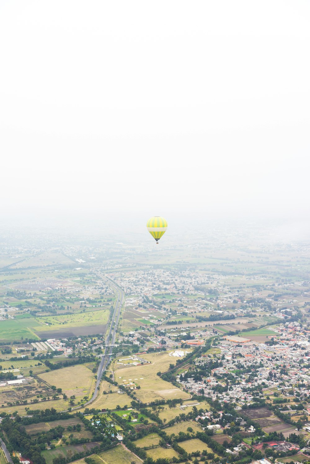 Foto eines gelben Heißluftballons, der über Häusern schwebt