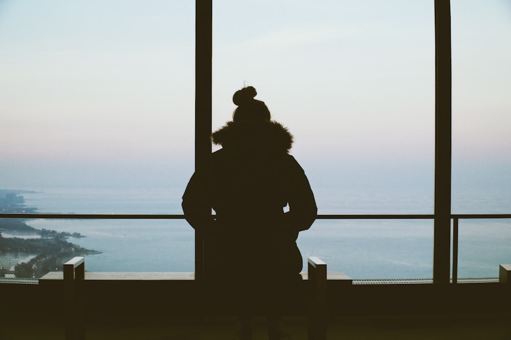 silhouette of woman standing overlooking body of water