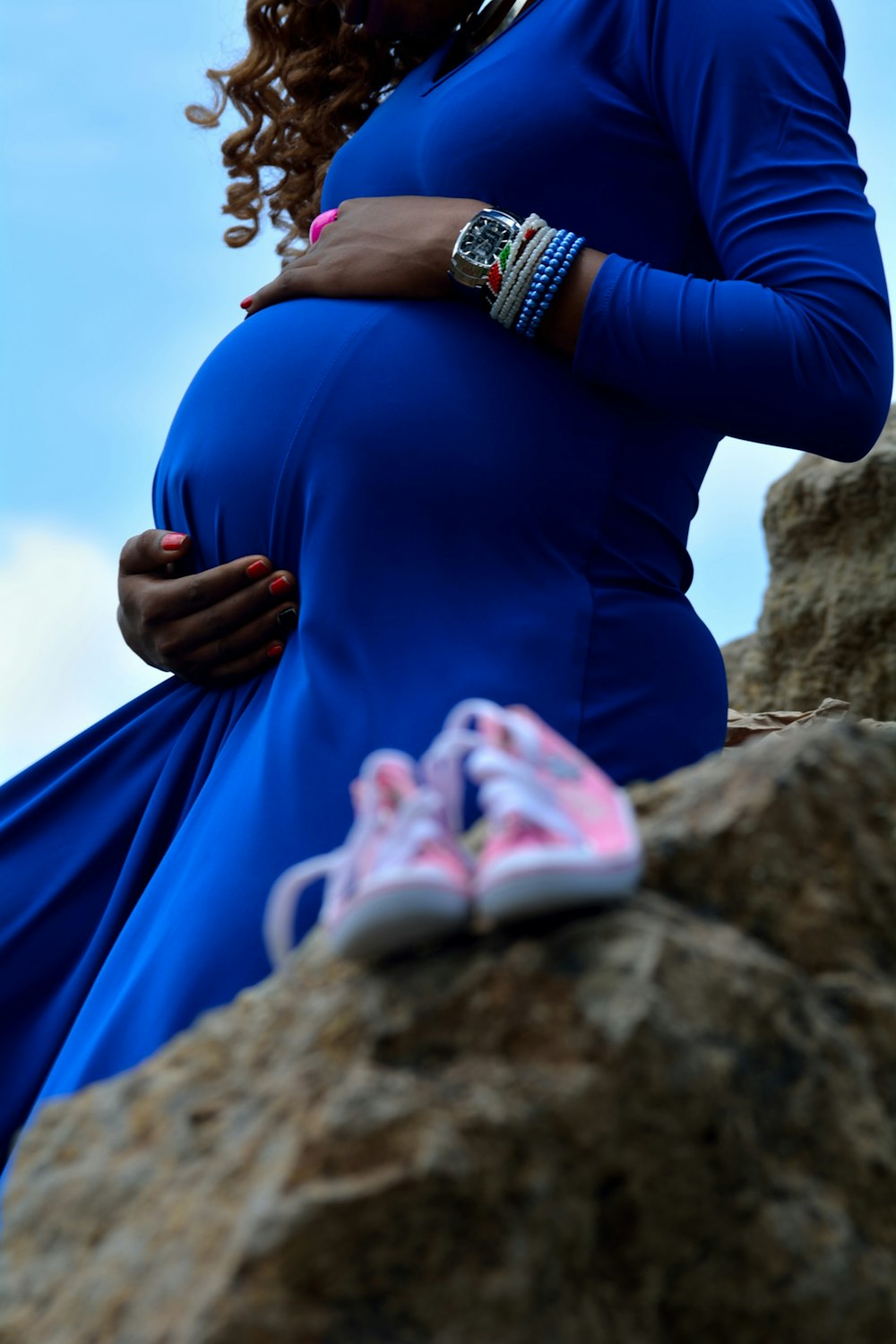 A pregnant woman's belly in a blue maternity dress.