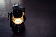 Close-up of an antique brass lantern glowing softly on a rustic wooden table.