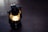 A vintage lantern with a lit bulb casting a warm glow, placed on a dark wooden surface.