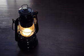 A repaired antique lamp glowing warmly on a wooden side table.