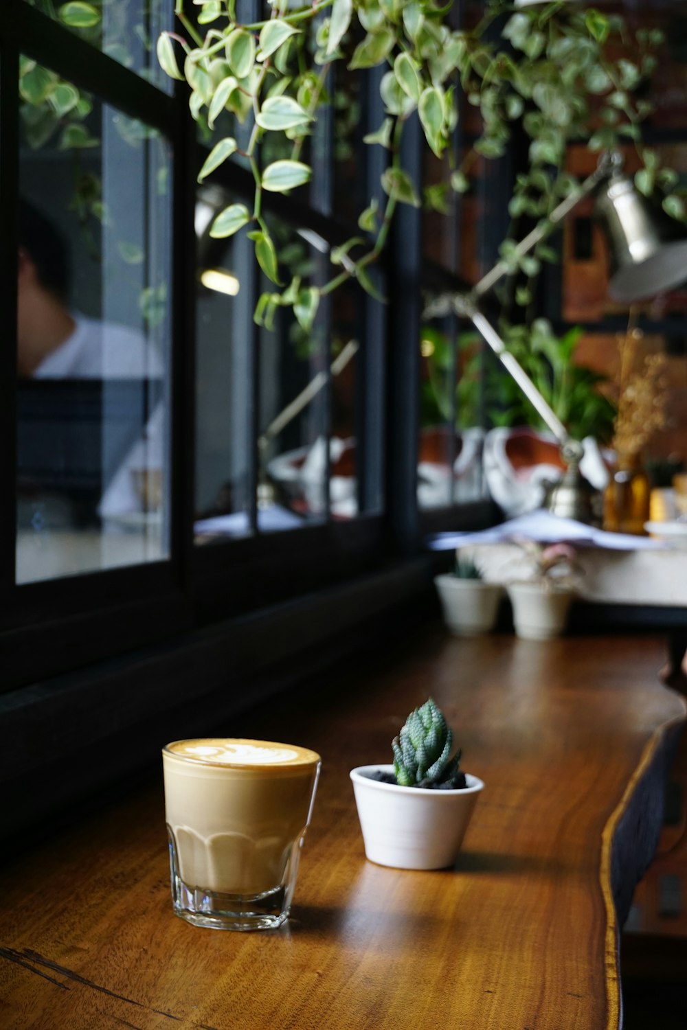 Café con leche y cactus sobre mesa de madera marrón