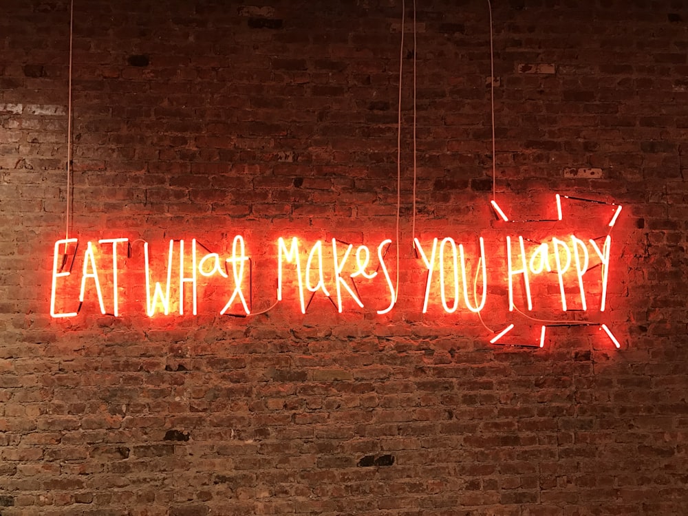 Señalización de neón iluminada para comer lo que te hace feliz