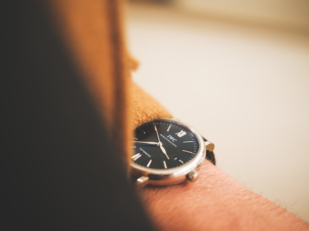 person holding round silver analog watch