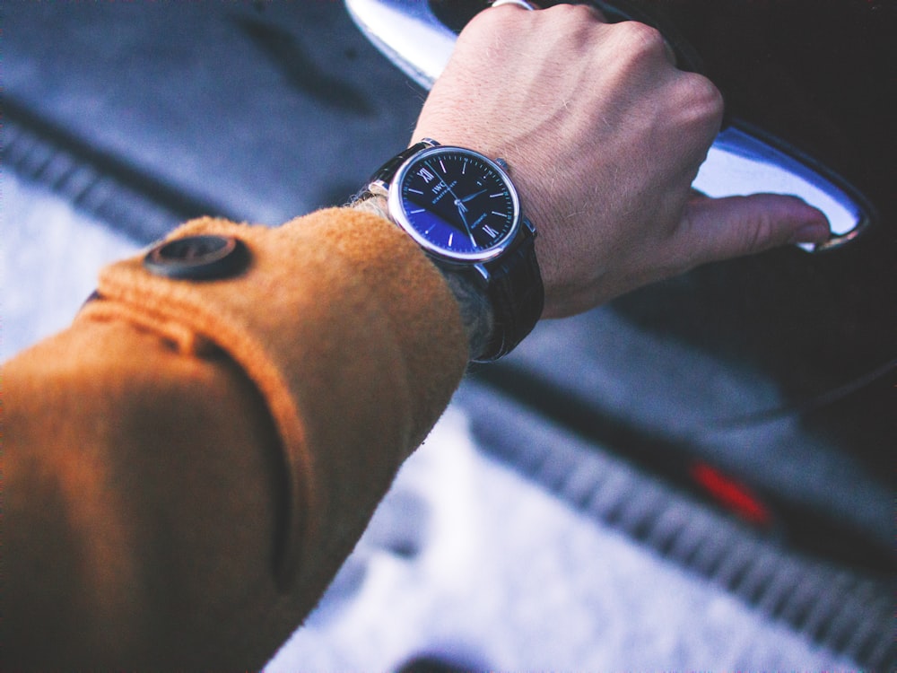 person holding car door lever wearing round silver-colored watch