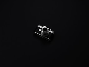 A minimalist black and white photo of a vintage camera on a grey background.