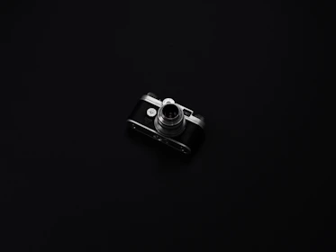 An elegant dark background with warm gold accents highlighting a vintage camera and film strips.
