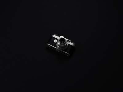A minimalist dark room showcasing a vintage camera and framed black-and-white photographs.