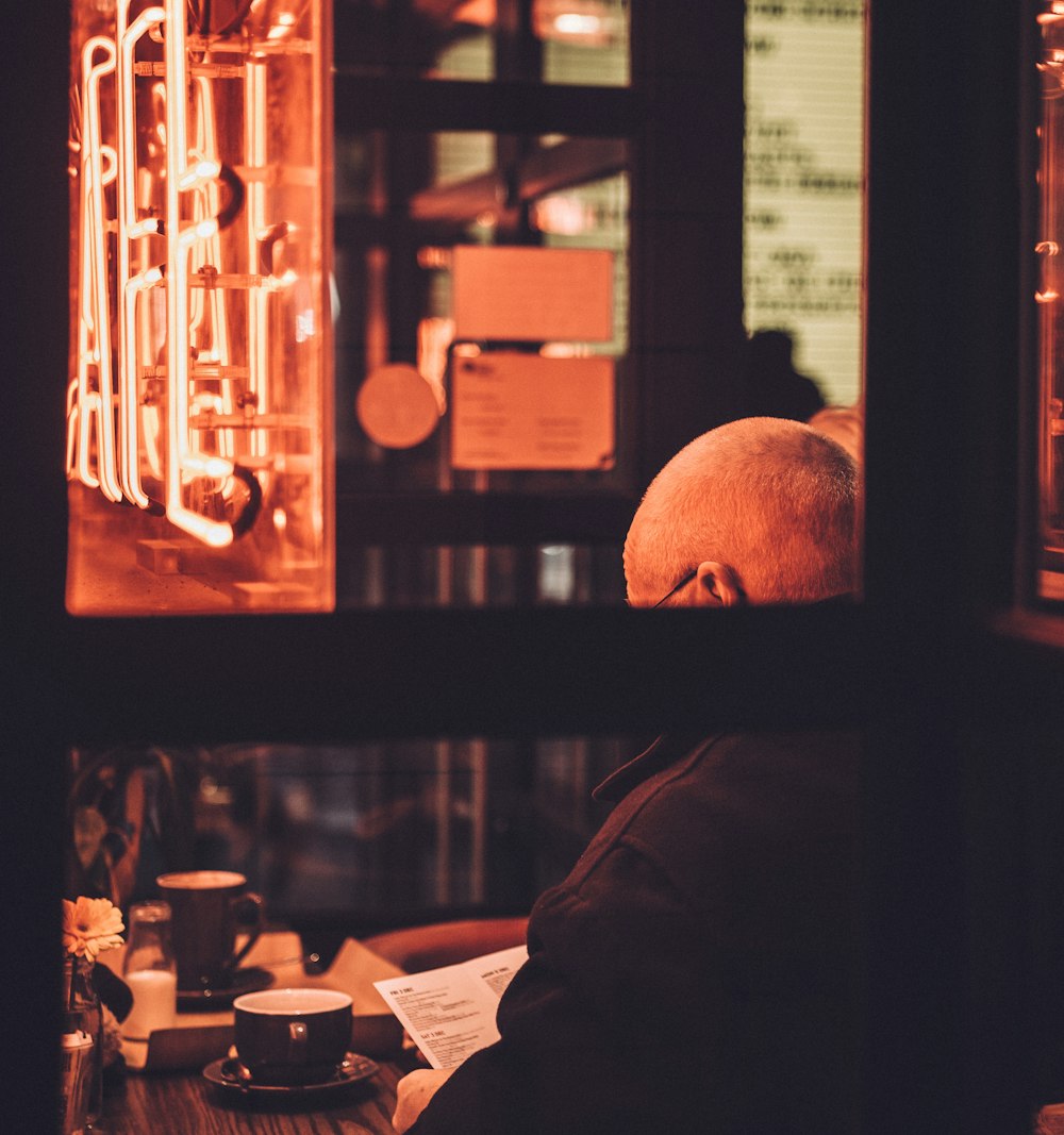 man sitting on chair reading book in front of table