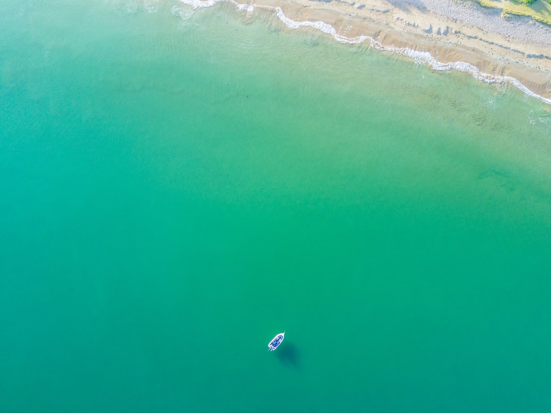 aerial photography of white boat on green ocean near seashore, Drone view of boat in ocean