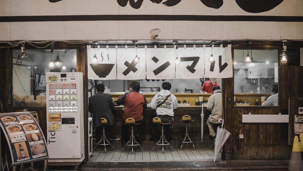 Cuatro personas sentadas en taburetes de bar