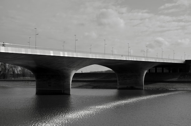 A newly constructed bridge spanning a river, showcasing solid concrete pillars and smooth road surface.