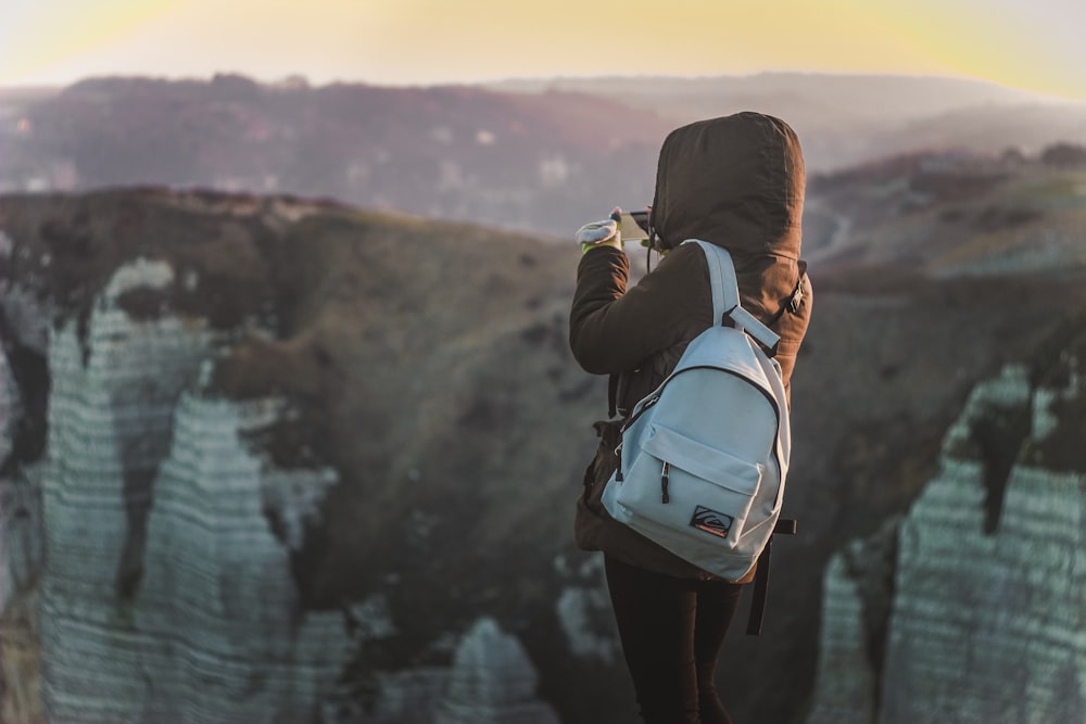 person standing near cliff holding camera