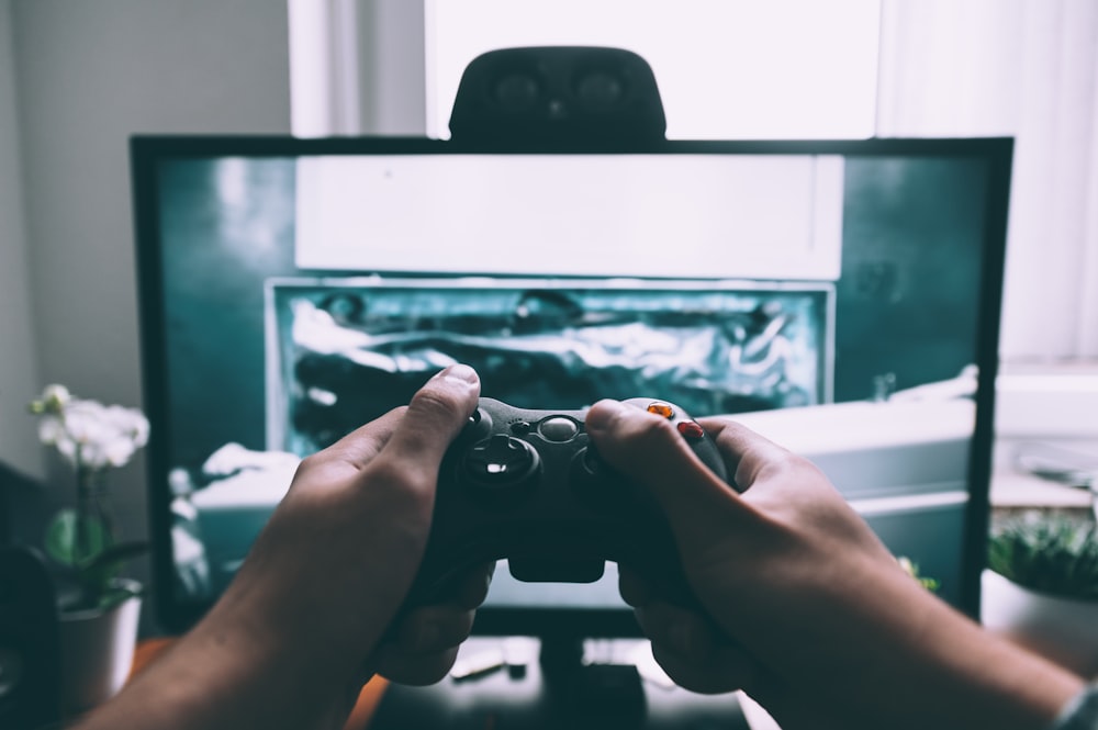 Persona che tiene il controller di gioco davanti alla televisione