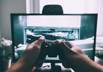 person holding game controller in-front of television