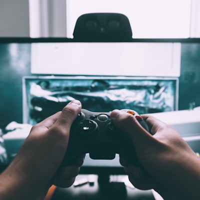 person holding game controller in-front of television