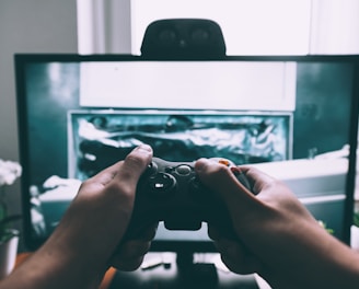 person holding game controller in-front of television