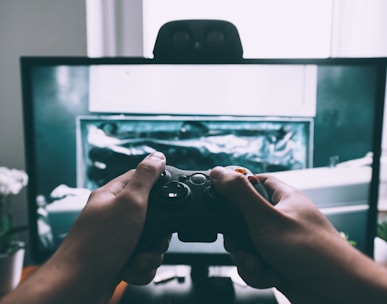 person holding game controller in-front of television