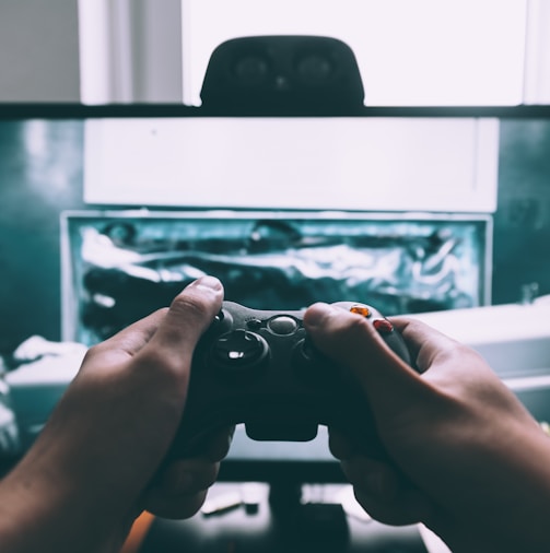 person holding game controller in-front of television