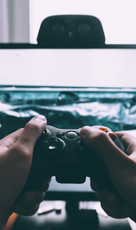 person holding game controller in-front of television