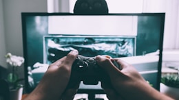 person holding game controller in-front of television