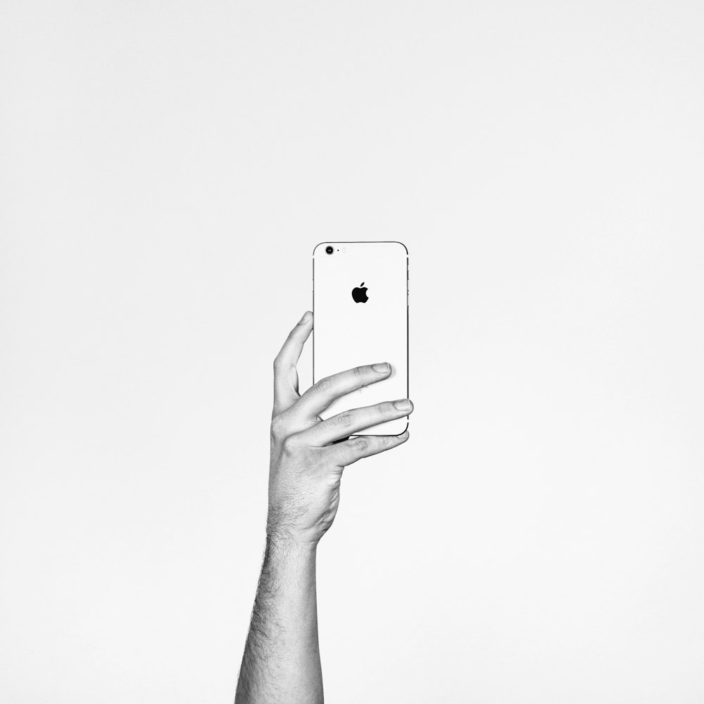 A person holding up an Apple phone.