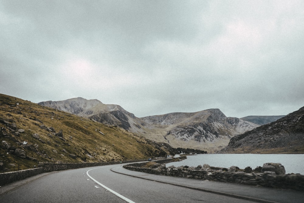 landscape photography of road near mountain under cloudy sky