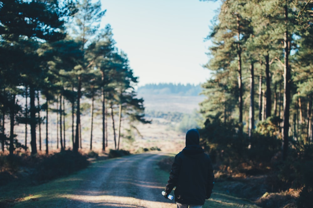 person wearing jacket walking on dirt road