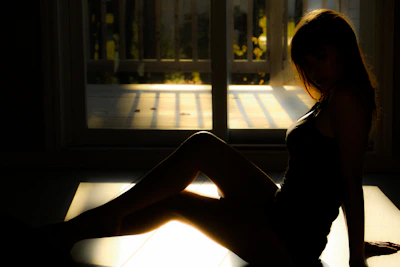 Soft natural light illuminating a silhouette in a calm, meditative posture in a quiet room.