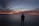 silhouette of person standing near calm body of water during golden hour
