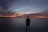 silhouette of person standing near calm body of water during golden hour
