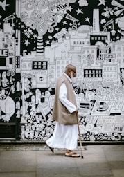 man wearing white sherwani robe beside graffiti