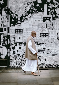 man wearing white sherwani robe beside graffiti