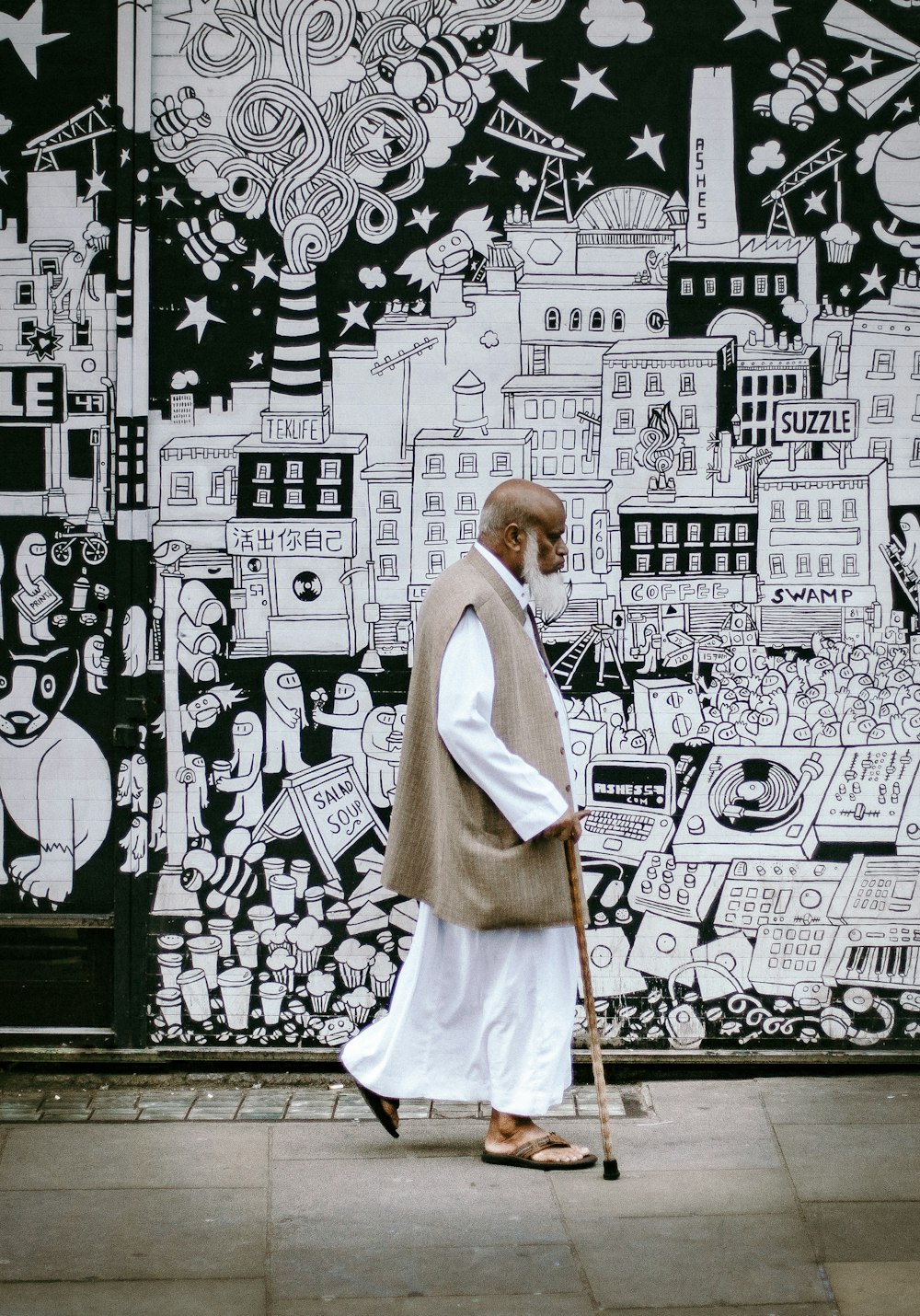 man wearing white sherwani robe beside graffiti