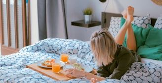 Woman lying on bed enjoying breakfast