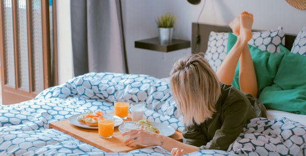 Woman lying on bed enjoying breakfast