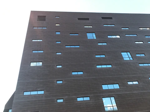 A sleek, modern building facade with dark gray and anthracite tones highlighting natural textures.