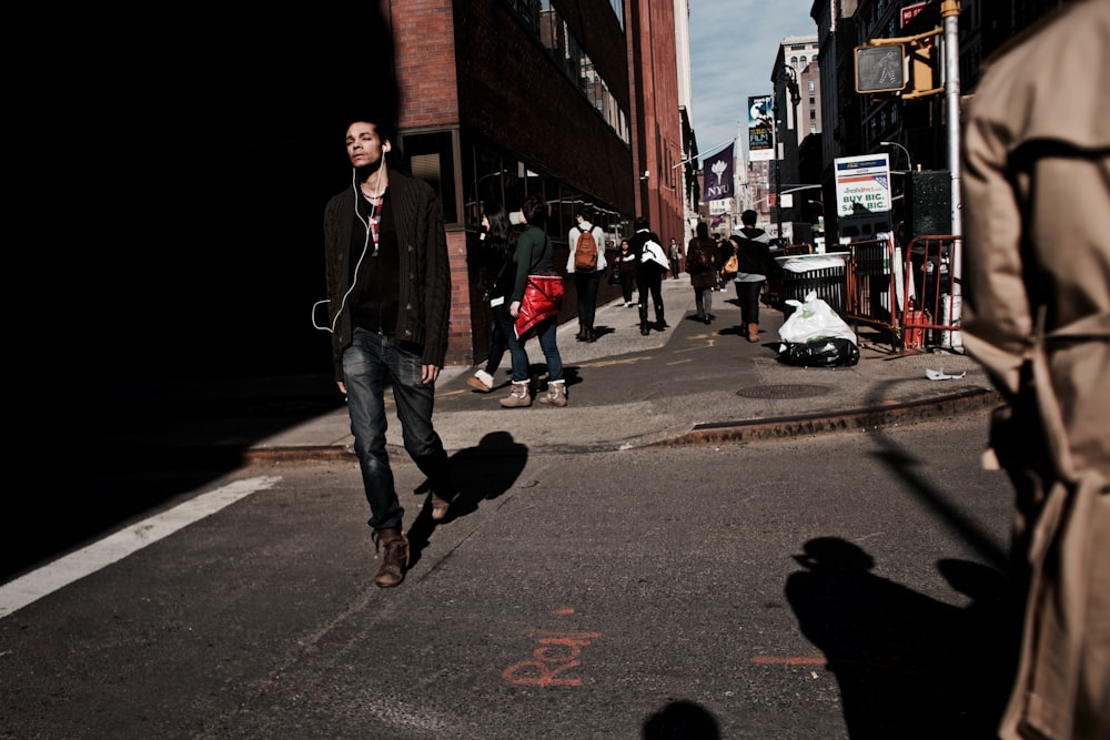 man walking on road using earbuds